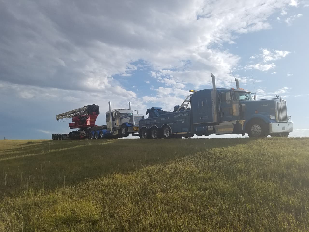 Western Towing wrecker and lowboy hauling a drilling rig across the plains
